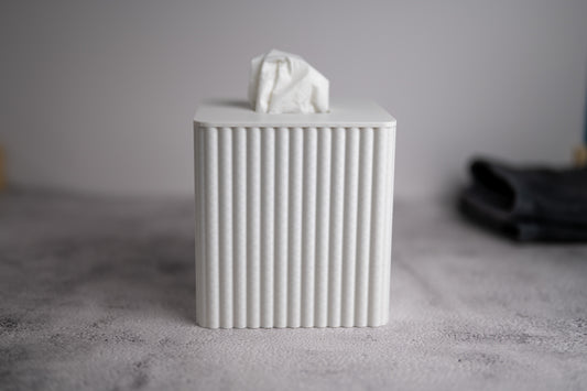White ribbed tissue box with a tissue on top against a neutral background